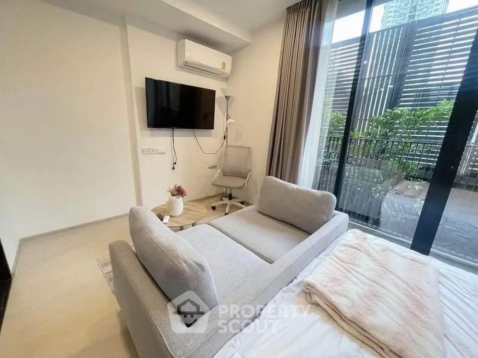Modern living room with balcony access, featuring sleek furniture and natural light.