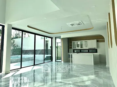 Luxurious open-plan living room with marble floors and modern kitchen overlooking a private pool.