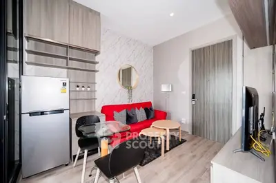 Modern living room with red sofa, dining area, and sleek kitchen appliances in stylish apartment.