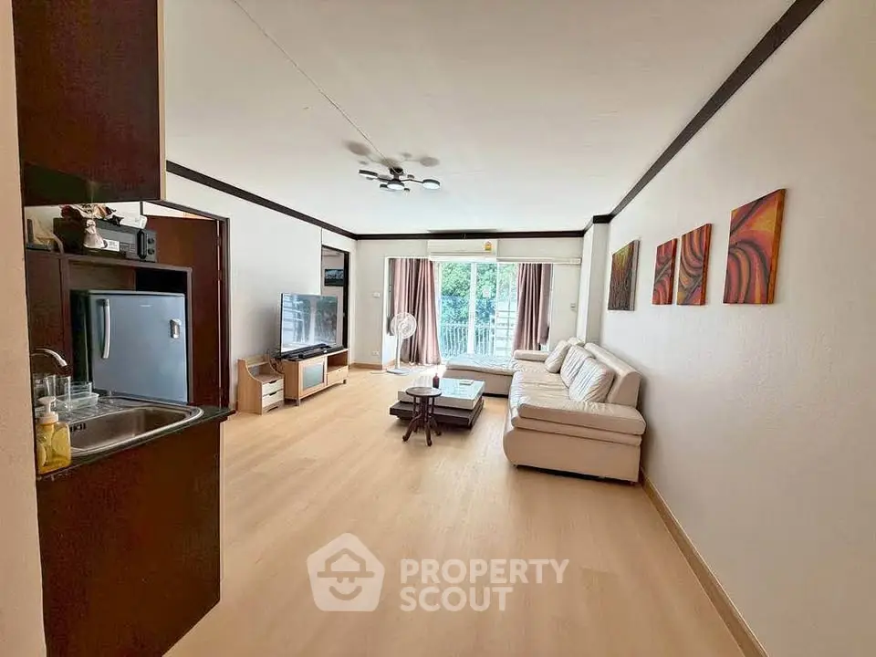 Spacious living room with modern decor and large windows offering natural light and a view.