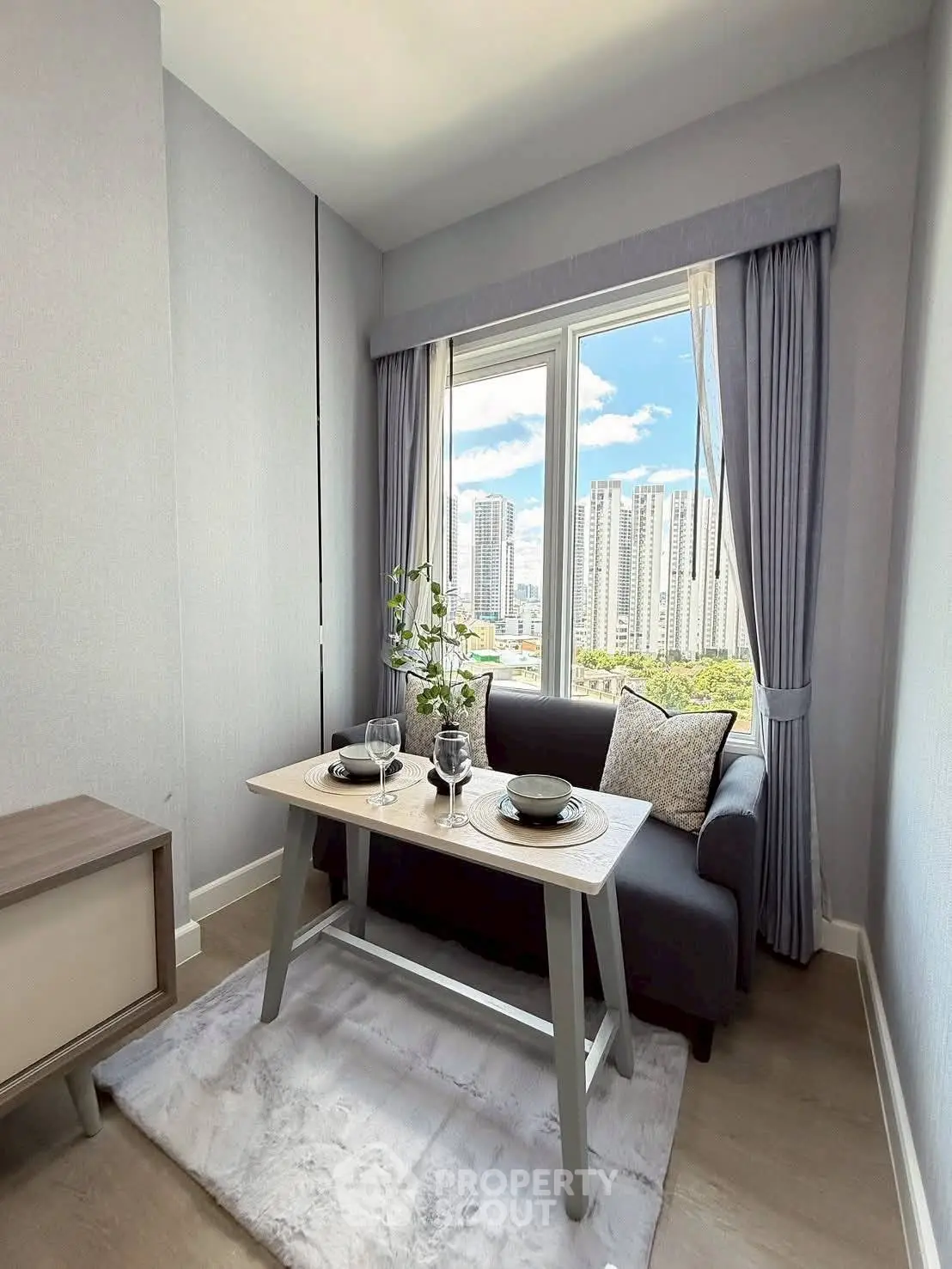 Chic urban living room with city view, modern decor, and cozy dining setup.