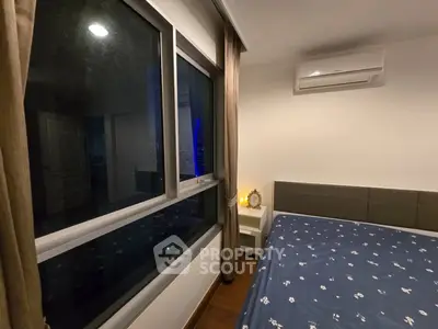 Cozy bedroom with large window and air conditioning unit, perfect for relaxation.