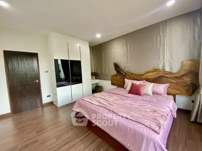 Spacious bedroom with elegant decor and wooden flooring, featuring a large bed and stylish wardrobe.