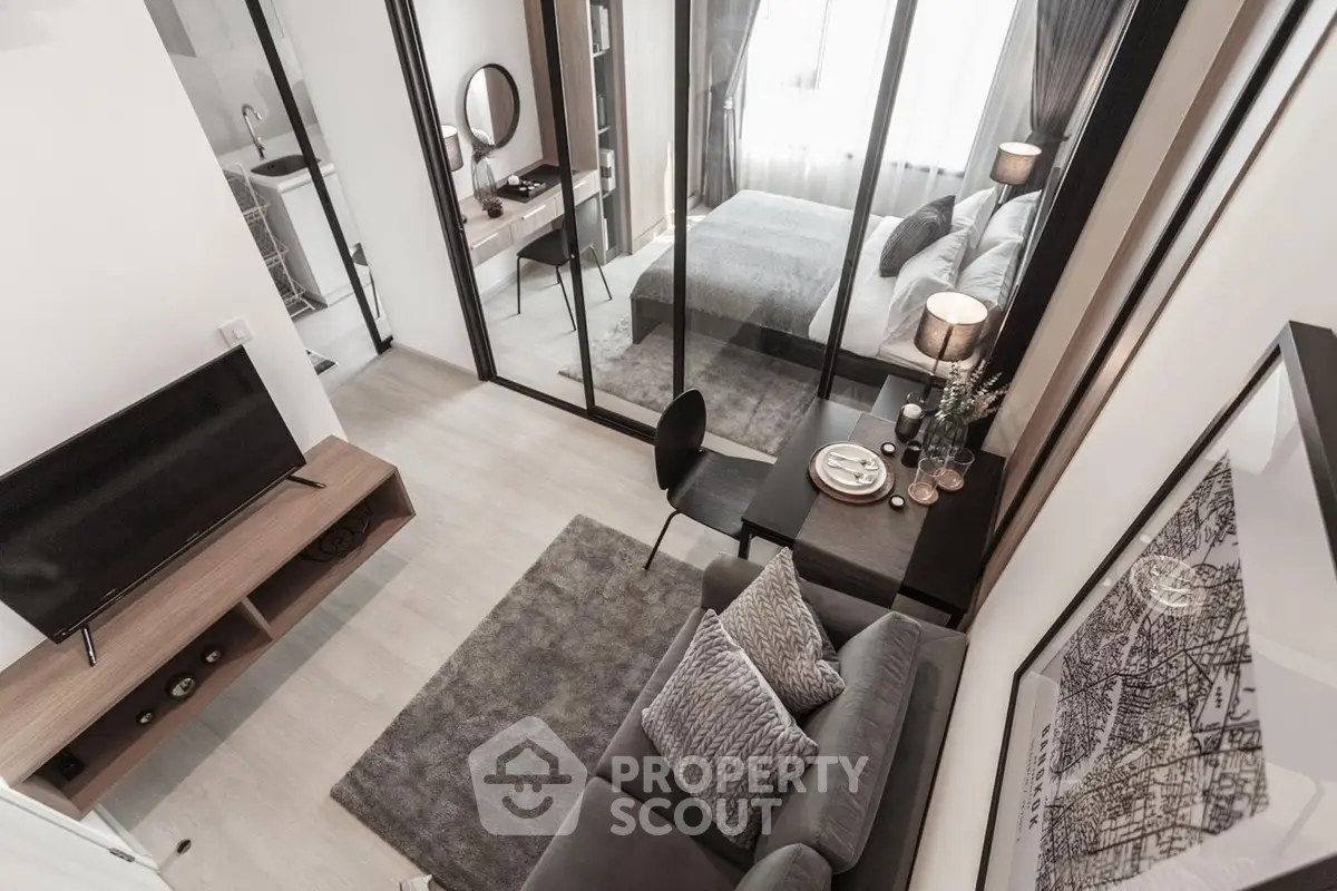 Modern studio apartment with stylish decor, featuring a cozy living area and a chic bedroom separated by glass doors.