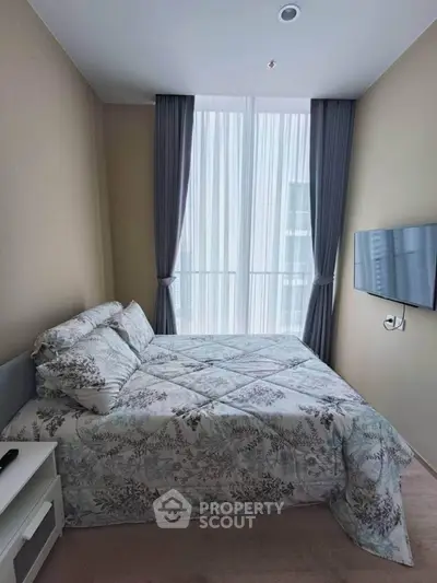 Cozy bedroom with elegant curtains and wall-mounted TV, perfect for relaxation.