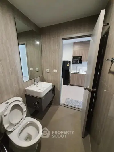 Modern bathroom with sleek fixtures and view into contemporary kitchen
