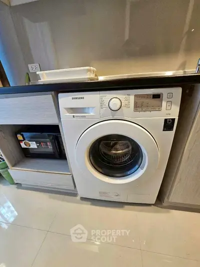 Modern kitchen with built-in Samsung washing machine and sleek cabinetry.