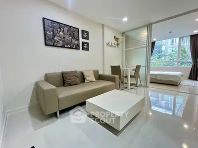 Modern open-plan living room with sleek furniture and large windows offering natural light.