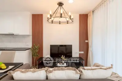 Modern living room with stylish chandelier and cozy sofa, featuring a sleek TV setup and elegant decor.
