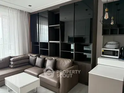 Modern living room with sleek furniture and built-in shelving, featuring a cozy sectional sofa and contemporary lighting.