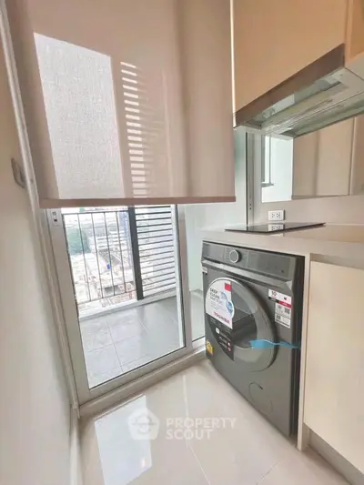 Modern kitchen with washing machine and balcony view in high-rise apartment