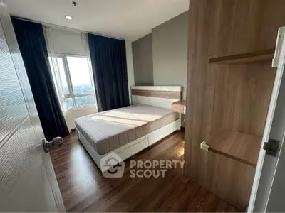 Modern bedroom with wooden flooring and large window offering scenic views