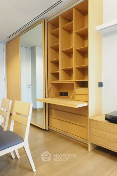 Modern study area with built-in wooden shelves and desk in a stylish apartment.