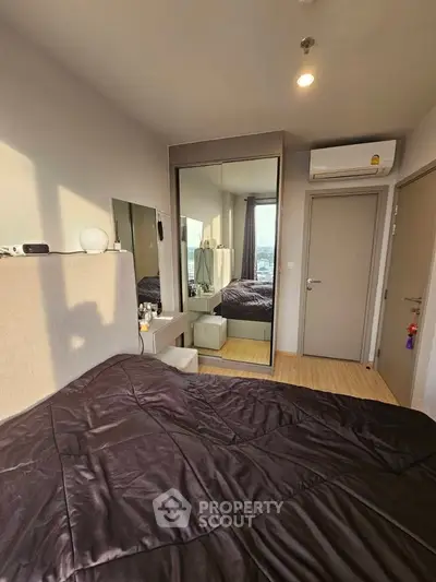 Modern bedroom with stylish decor and large mirror reflecting natural light.