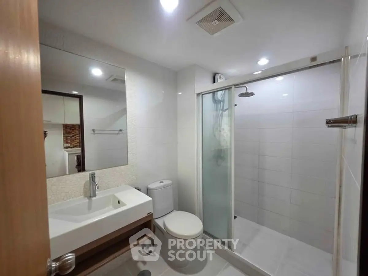 Modern bathroom with glass shower and sleek fixtures in a contemporary apartment.