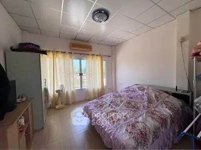 Cozy bedroom with floral bedding and natural light from large window
