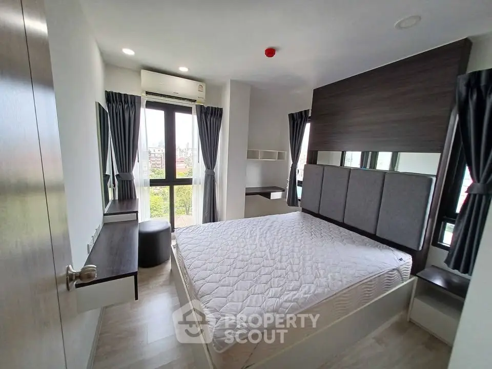 Modern bedroom with large windows and stylish decor in a high-rise apartment.