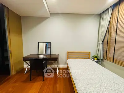 Cozy bedroom with wooden flooring, single bed, and study desk with mirror.