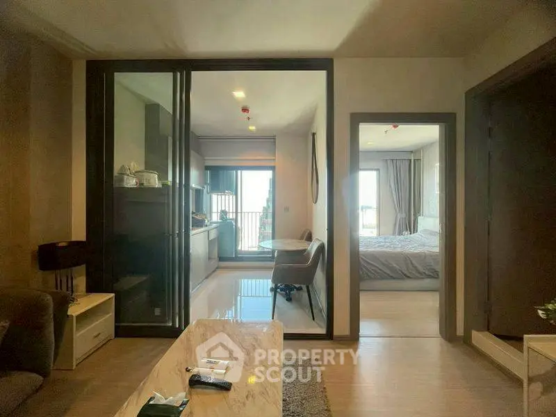 Modern apartment interior with open layout, featuring living room, kitchen, and bedroom with natural light.