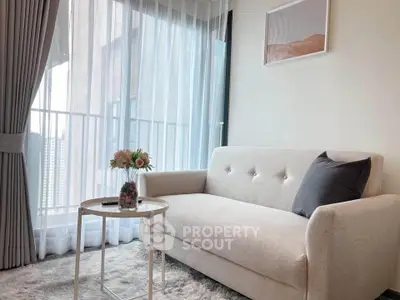 Chic living room with cozy sofa and elegant decor, featuring a bright window view.