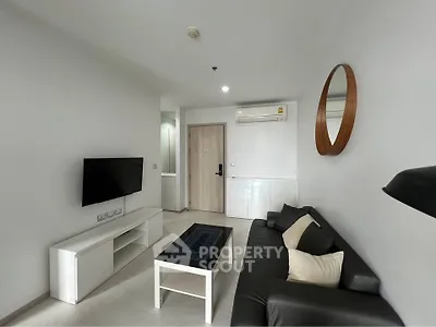 Modern living room with sleek black sofa, wall-mounted TV, and minimalist decor in a stylish apartment.