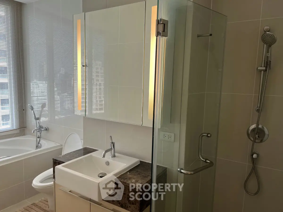 Modern bathroom with glass shower and bathtub in luxury apartment