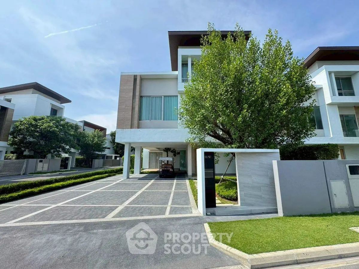 Luxurious modern villa with spacious driveway and lush greenery in an upscale neighborhood.