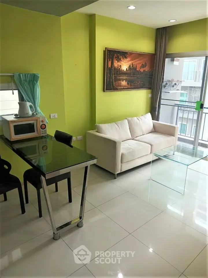 Modern living room with green walls, glass table, and balcony view