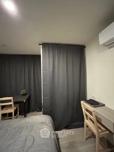 Cozy bedroom with modern decor and workspace, featuring a comfortable bed and stylish curtains.