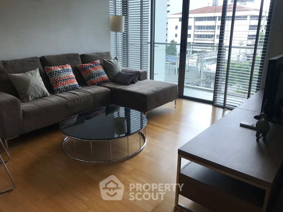 Modern living room with stylish sofa and city view balcony, perfect for urban living.