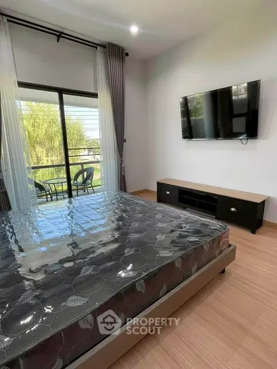 Modern bedroom with balcony view and wall-mounted TV