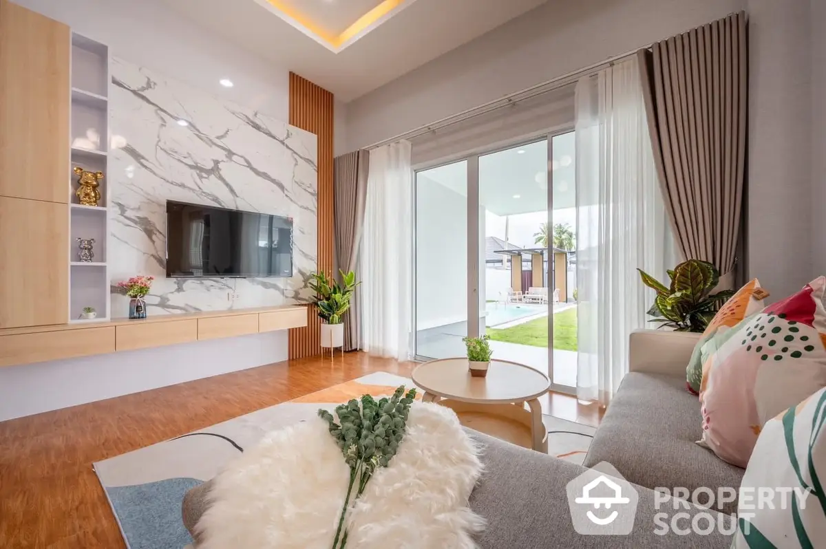 Elegant living room with modern design, featuring a plush sofa, sleek entertainment unit, and large windows leading to a serene outdoor view, perfect for comfortable urban living.