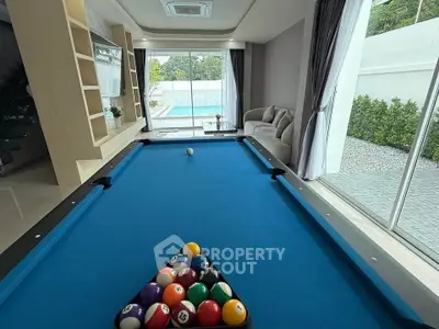 Luxurious living room with pool table and stunning pool view, perfect for entertainment and relaxation.