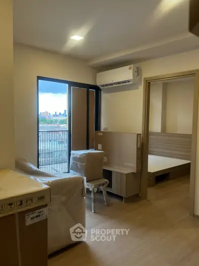 Modern apartment interior with balcony view and air conditioning, featuring a cozy living space and bedroom access.