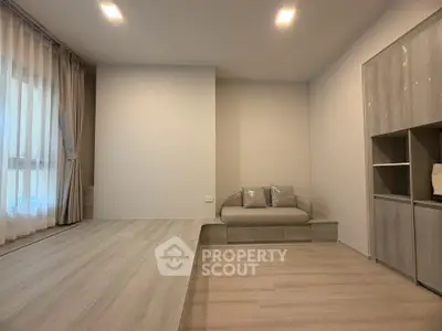 Modern minimalist living room with light wood flooring and cozy seating area.