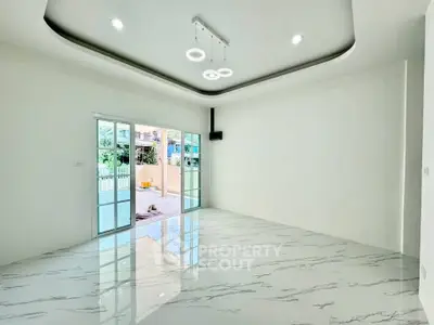 Spacious modern living room with marble flooring and stylish ceiling lights, opening to a patio.