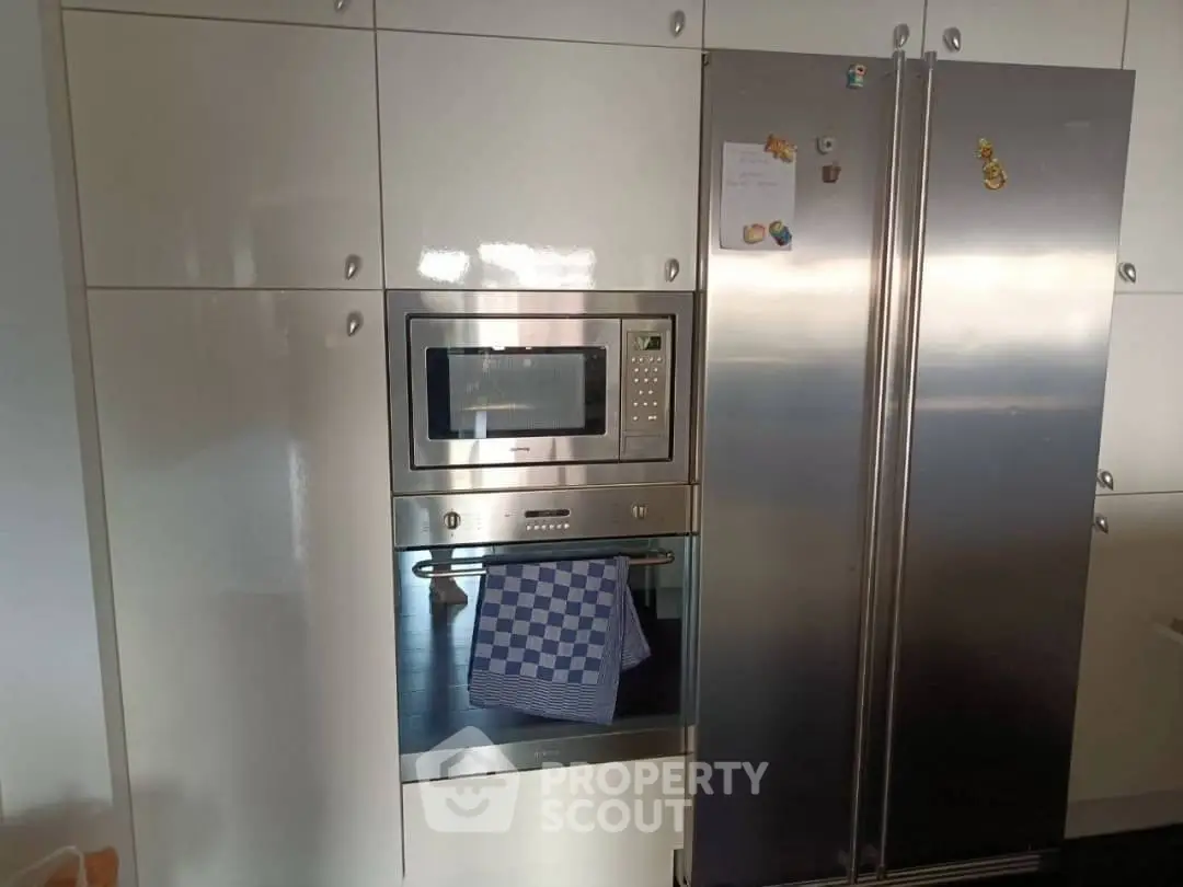 Modern kitchen with built-in microwave and stainless steel fridge