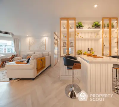 Bright and modern open-plan living space with a sleek kitchen, comfortable living area, and stylish bar stools, perfect for entertaining and relaxation.