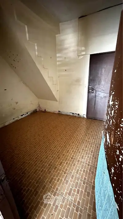 Compact storage room with tiled floor and staircase access, ideal for organizing household items.
