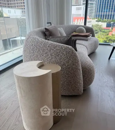 Modern living room with stylish curved sofa and city view, featuring elegant decor and natural light.