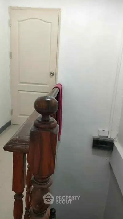 Charming interior stairway with wooden railing and white door, perfect for cozy home ambiance.