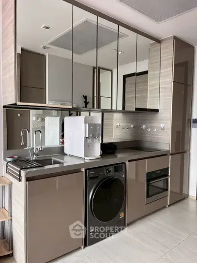 Modern kitchen with sleek cabinets, built-in oven, and washing machine, perfect for contemporary living.