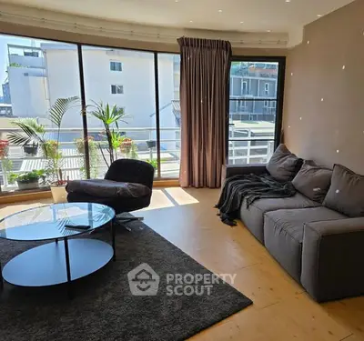 Spacious living room with large windows and modern furniture, offering a bright and inviting atmosphere.