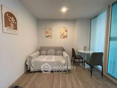 Cozy living room with modern decor and natural light, featuring a comfortable sofa and dining area.