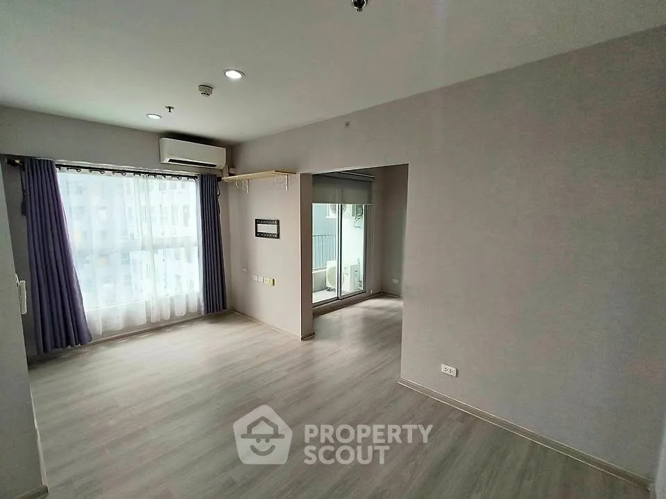 Spacious empty living room with large window and modern flooring in a bright apartment.