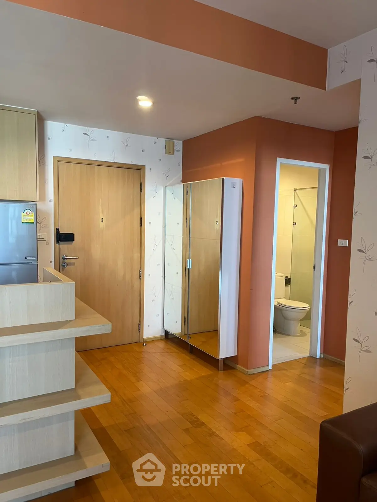 Charming apartment entrance with wooden flooring and mirrored closet