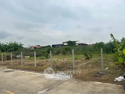 Vacant land plot with partial fencing and lush greenery, ideal for development opportunities.