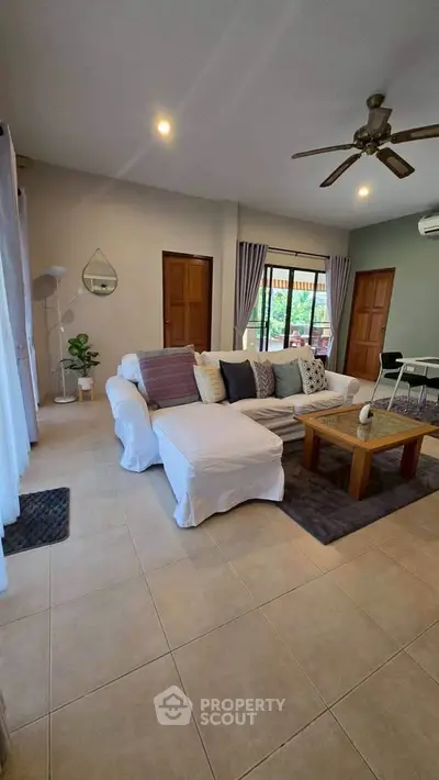 Spacious living room with cozy seating and natural light, perfect for relaxation and entertaining.