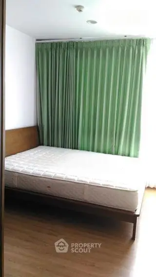 Spacious bedroom with green curtains and wooden flooring, perfect for a cozy retreat.