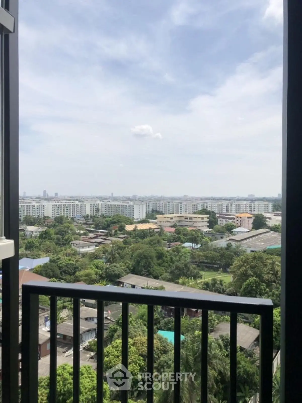Stunning cityscape view from a high-rise balcony overlooking lush greenery and urban skyline.